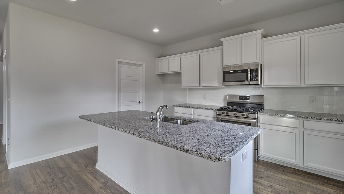 Kitchen and island with white cabinets and stainless steel appliances