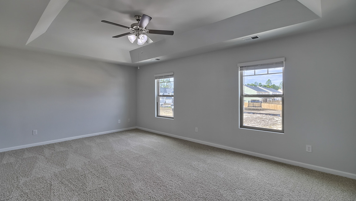 Primary bedroom with carpet, ceiling fan and large windows