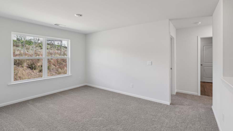 Carpeted loft area with windows