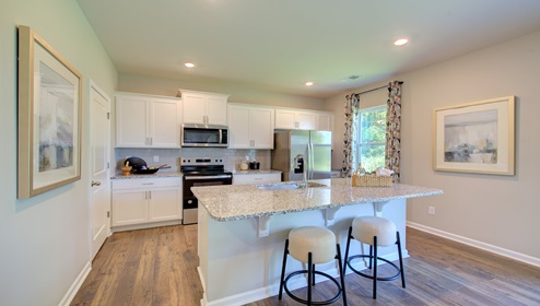 Kitchen and island with white cabinets, counters, and stainless steel appliances
