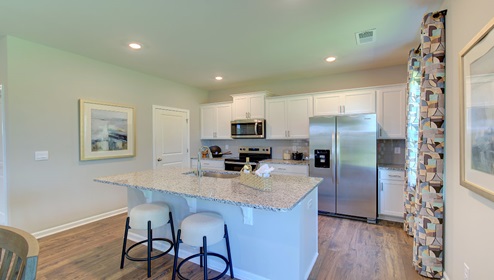 Kitchen and island with white cabinets, counters, and stainless steel appliances