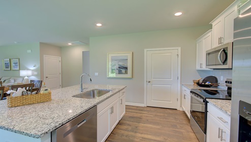 Kitchen and island with white cabinets, counters, and stainless steel appliances
