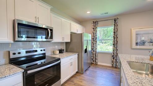Kitchen and island with white cabinets, counters, and stainless steel appliances