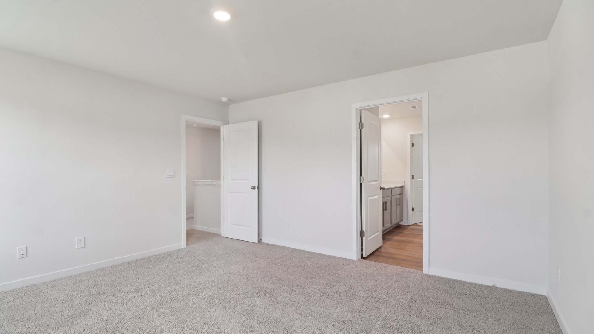Carpeted primary bedroom with attached bathroom