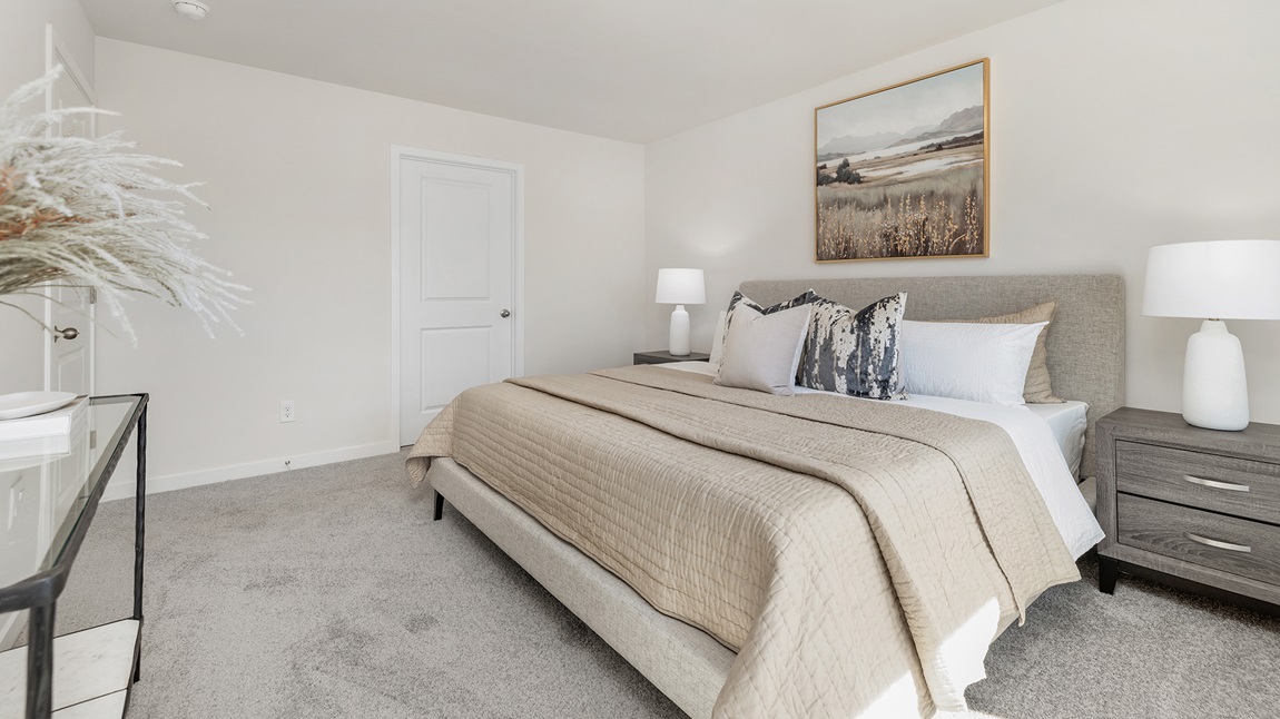 Carpeted primary bedroom with large windows