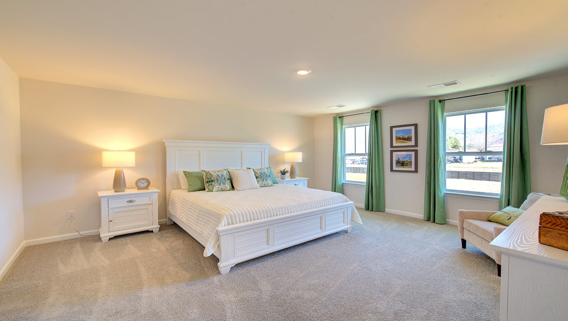 Carpeted primary bedroom with large windows