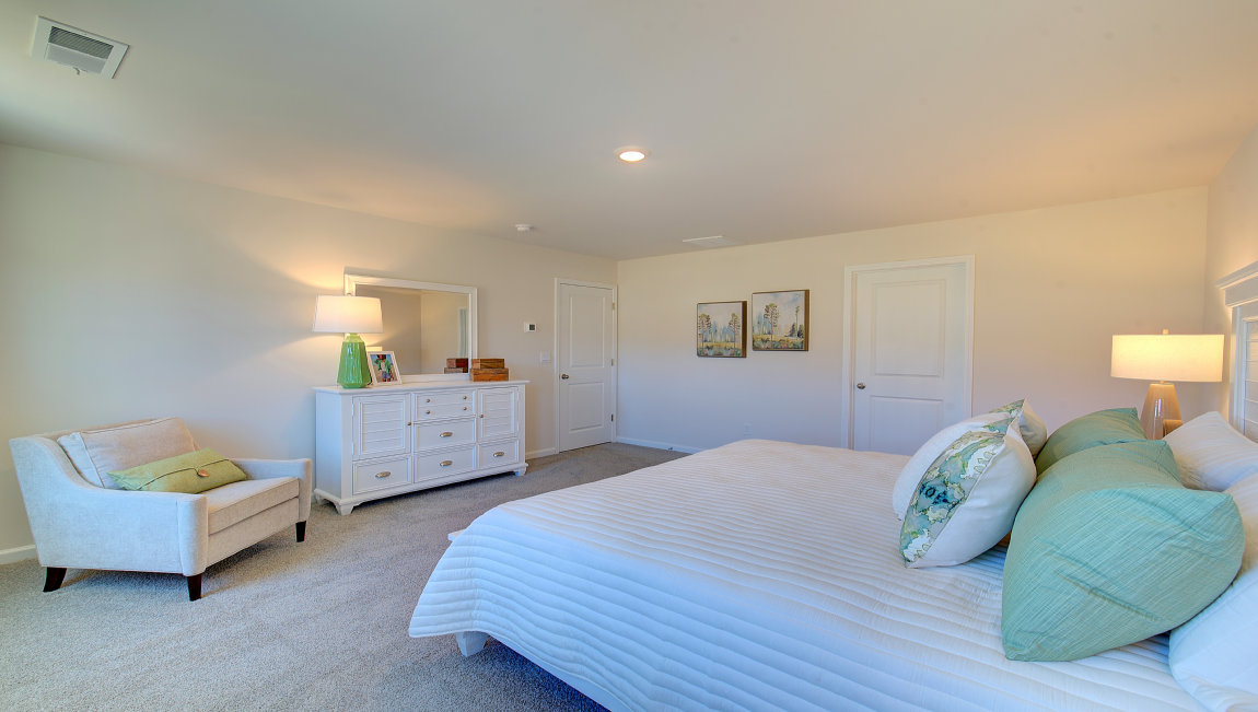 Carpeted primary bedroom with large windows