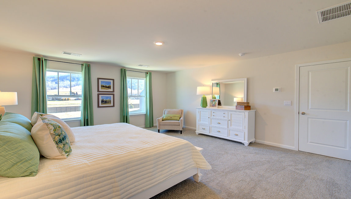 Carpeted primary bedroom with large windows