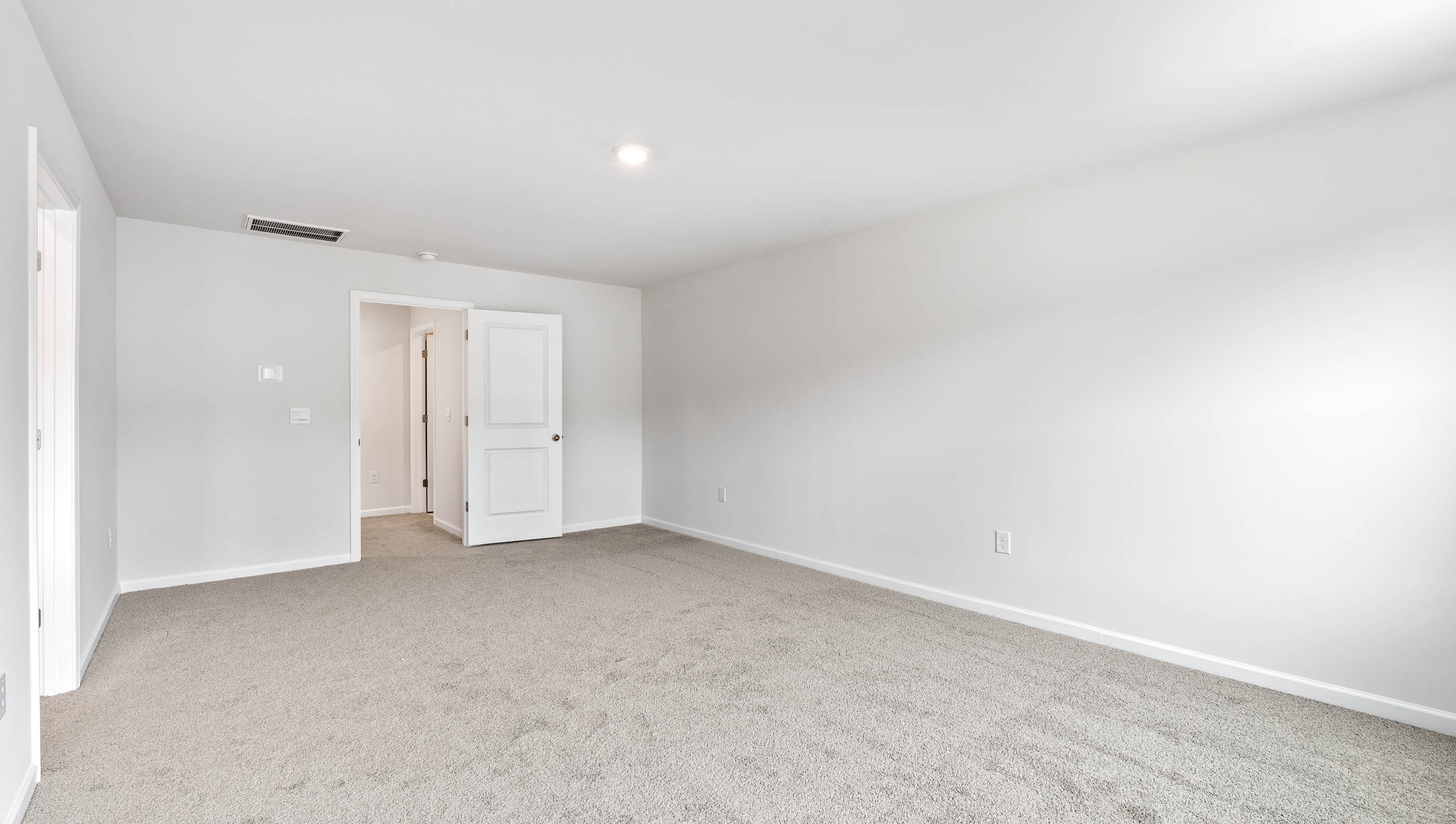 Primary carpeted bedroom with attached bathroom