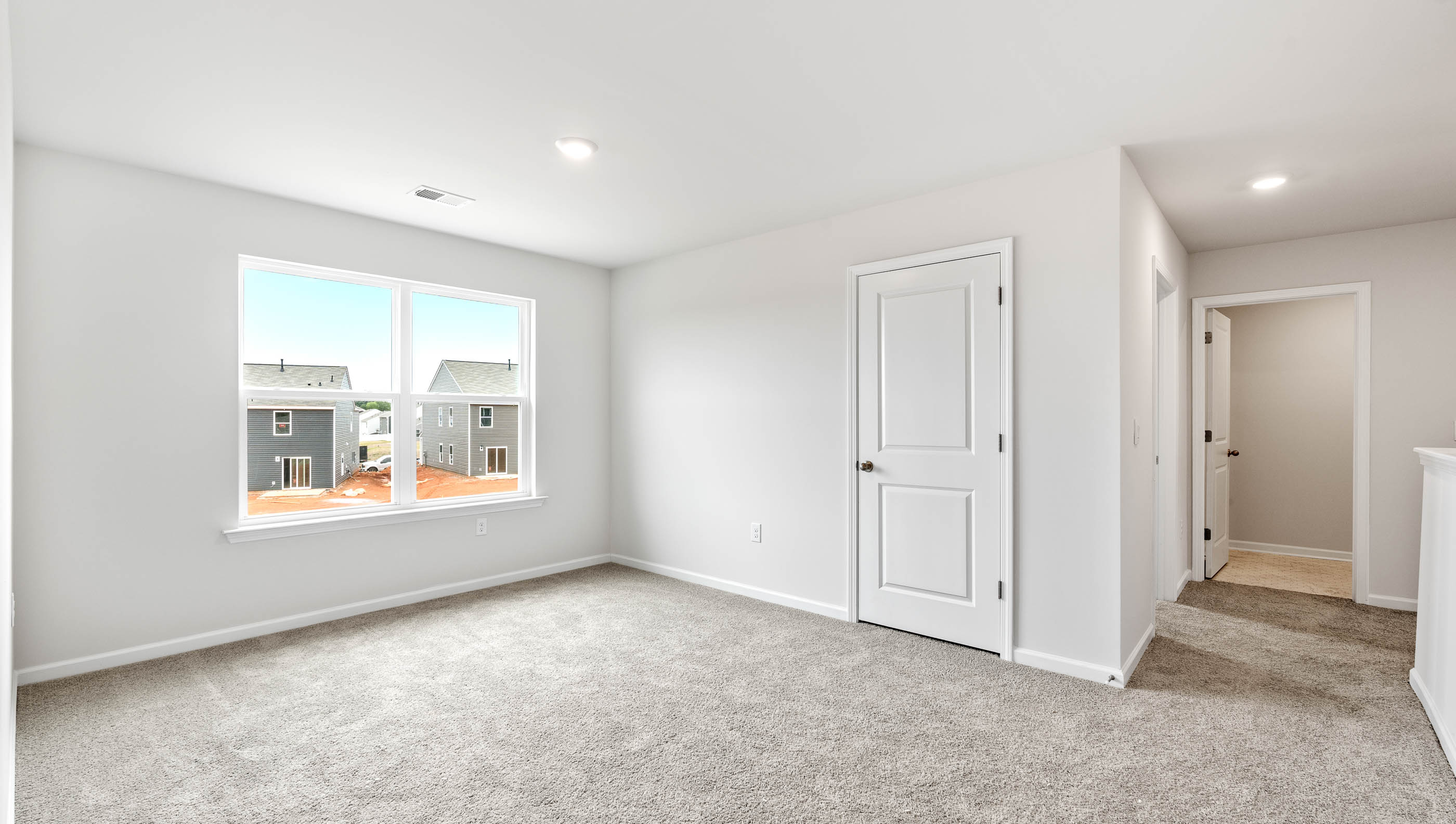 Carpeted primary bedroom with large windows