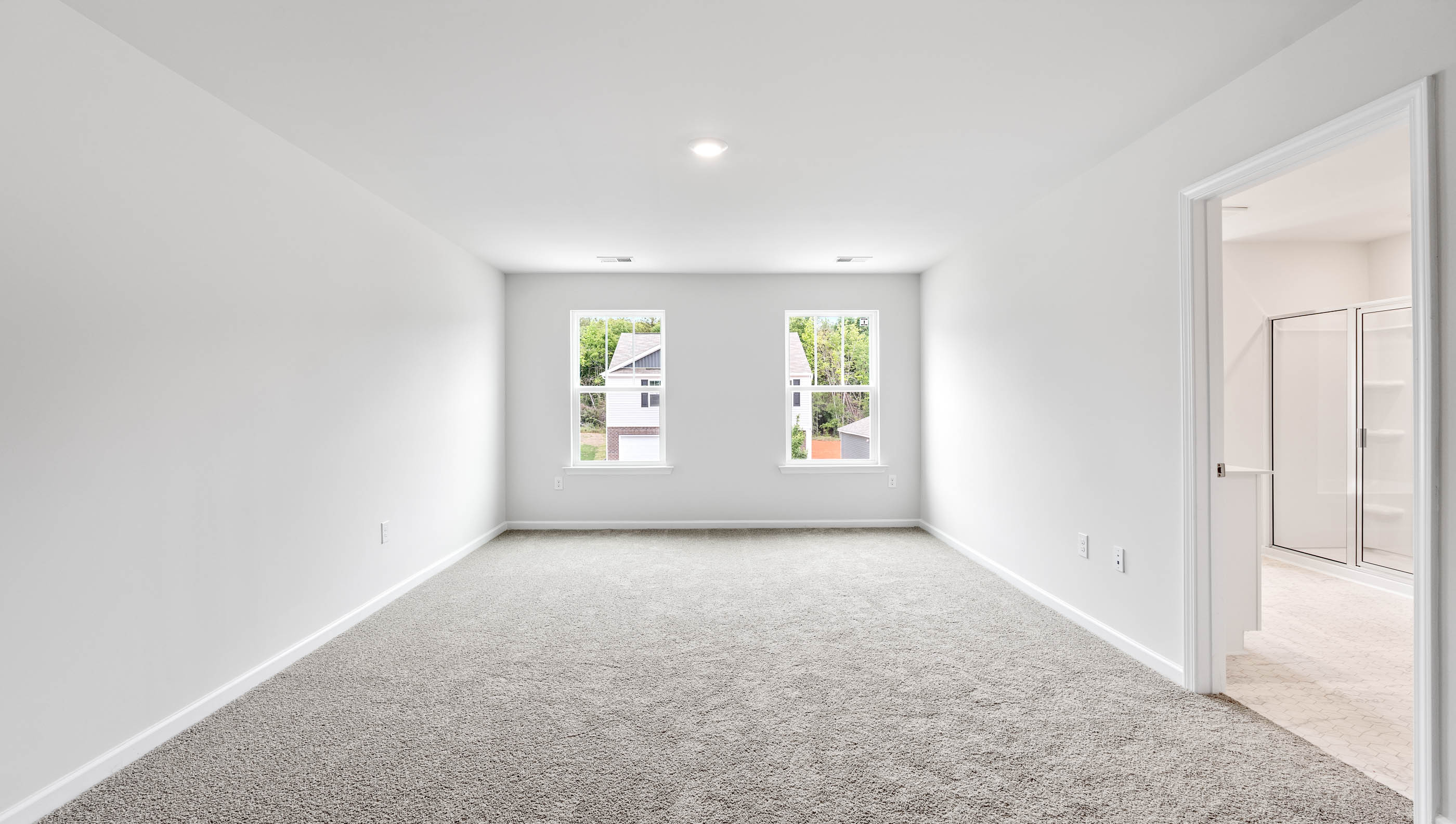 Carpeted primary bedroom with large windows