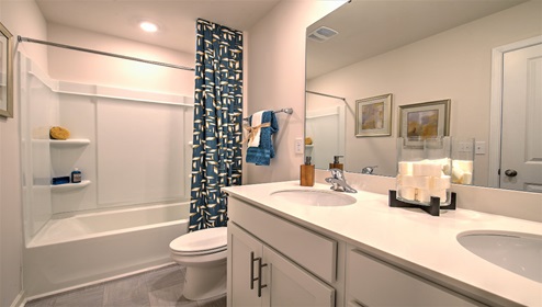 Bathroom with bathtub, double sinks and white counters and cabinets