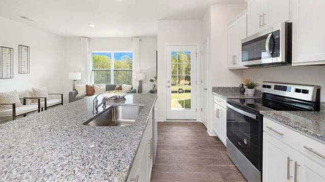 Kitchen and island with white cabinets, subway tile backsplash, and stainless steel appliances