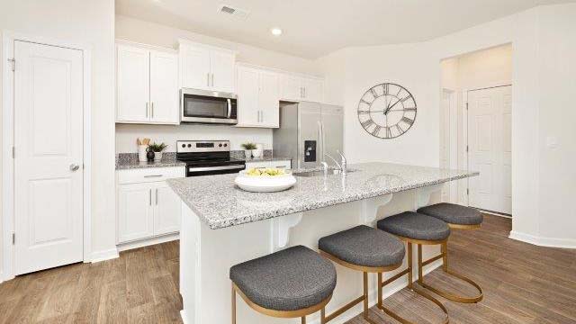 Kitchen and island with white cabinets, subway tile backsplash, and stainless steel appliances