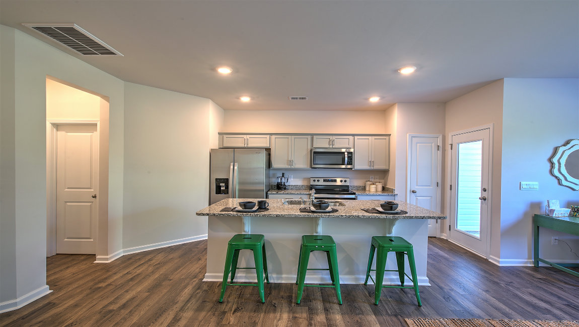 Kitchen and island with white cabinets, subway tile backsplash, and stainless steel appliances