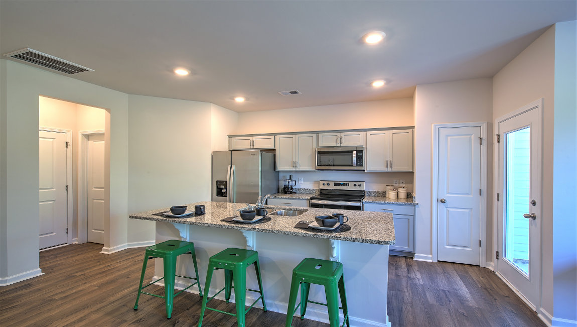 Kitchen and island with white cabinets, subway tile backsplash, and stainless steel appliances
