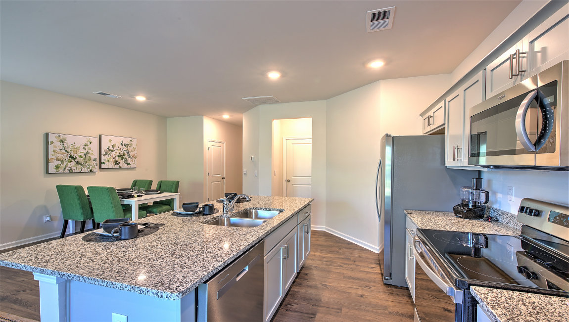 Kitchen and island with white cabinets, subway tile backsplash, and stainless steel appliances