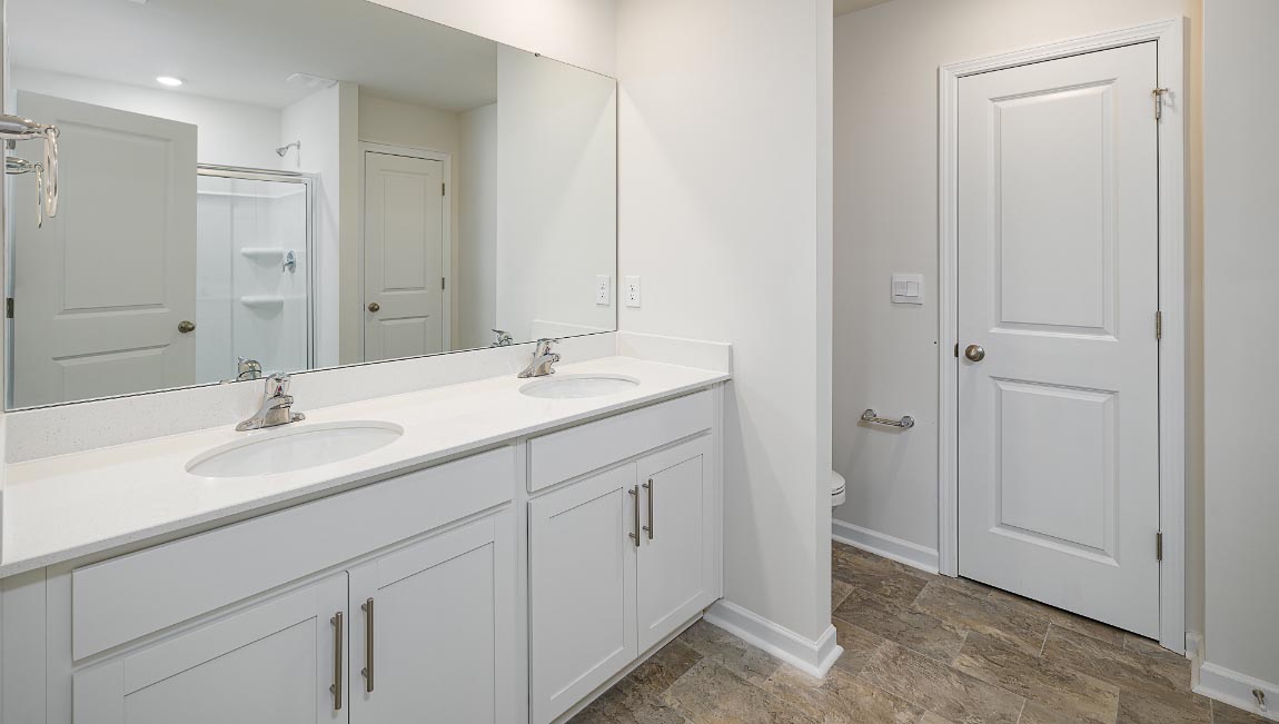 Primary bathroom with double sinks, white cabinets and counters