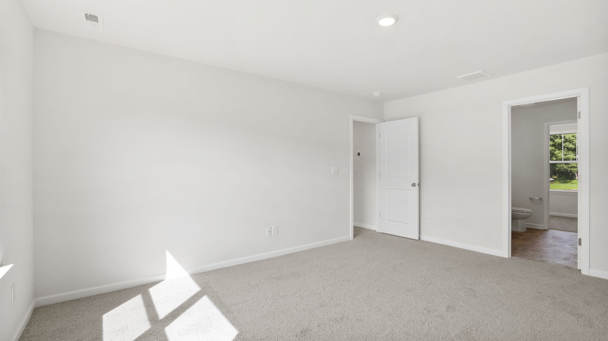 Carpeted primary bedroom with attached bathroom
