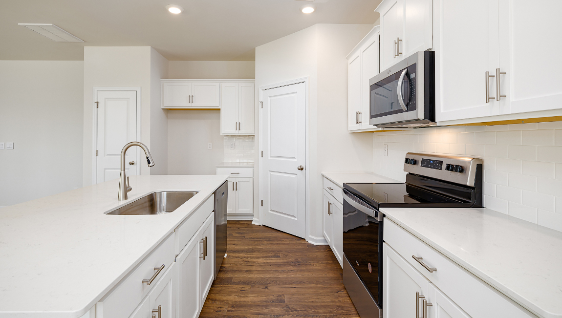 Kitchen and island with white cabinets, quartz counters, wood floors and stainless steel appliances