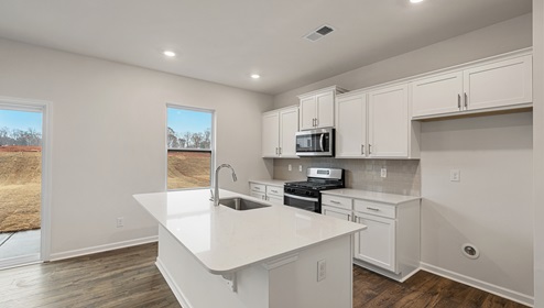 Kitchen and island with white cabinets and countertops, and stainless steel appliances.