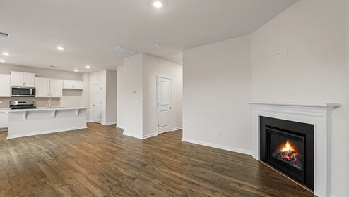 Open and spacious living room with wood floors and fireplace, beside kitchen
