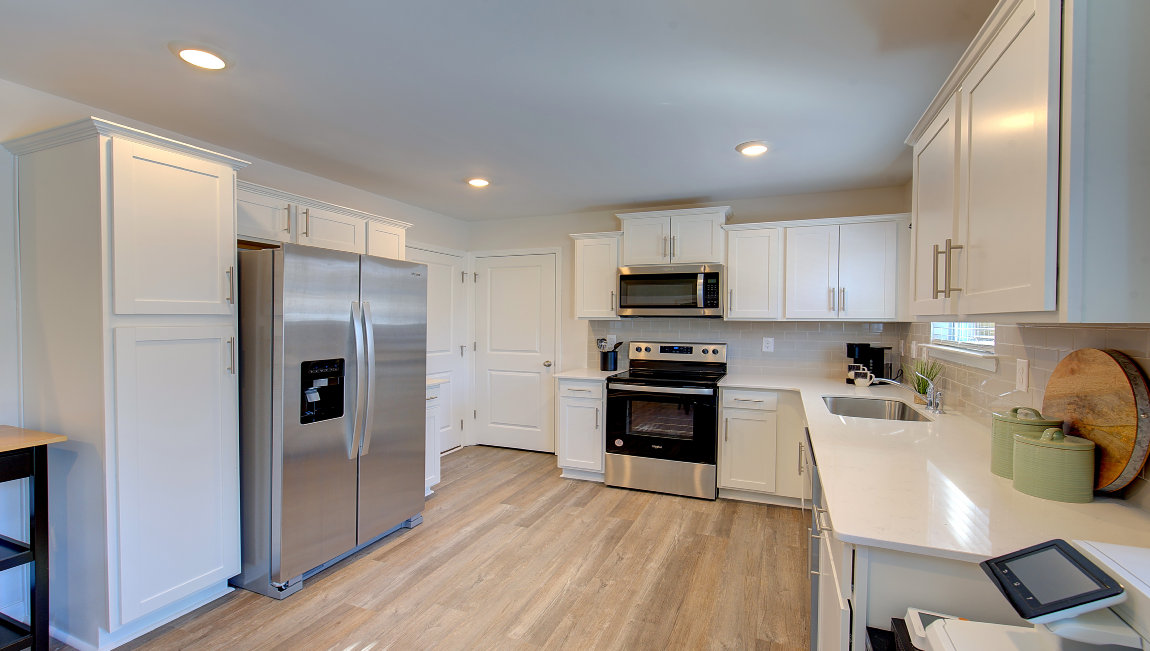 Kitchen with white cabinets, granite counters, subway tile backsplash and stainless steel appliances. New Homes in Asheville, North Carolina