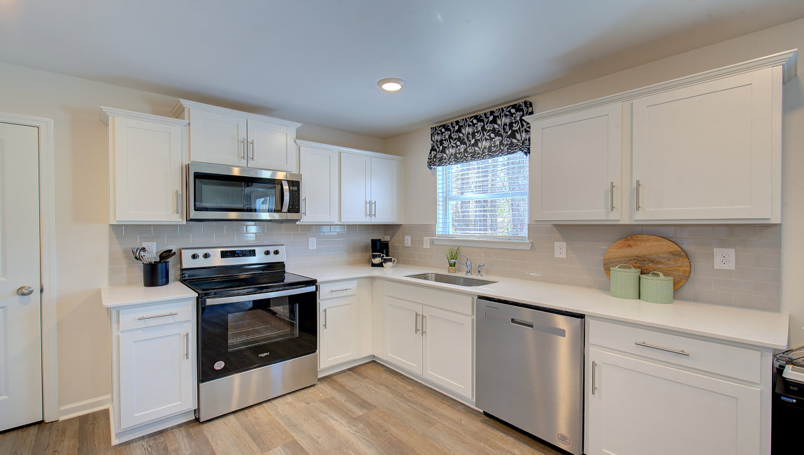 Kitchen with white cabinets, granite counters, subway tile backsplash and stainless steel appliances. New Homes in Asheville, North Carolina