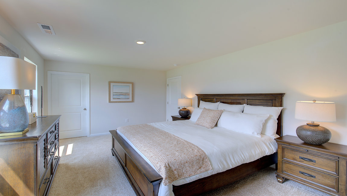 Primary bedroom with beige carpet and two windows. New Homes in Asheville, North Carolina