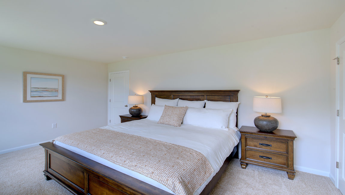 Primary bedroom with beige carpet and two windows. New Homes in Asheville, North Carolina