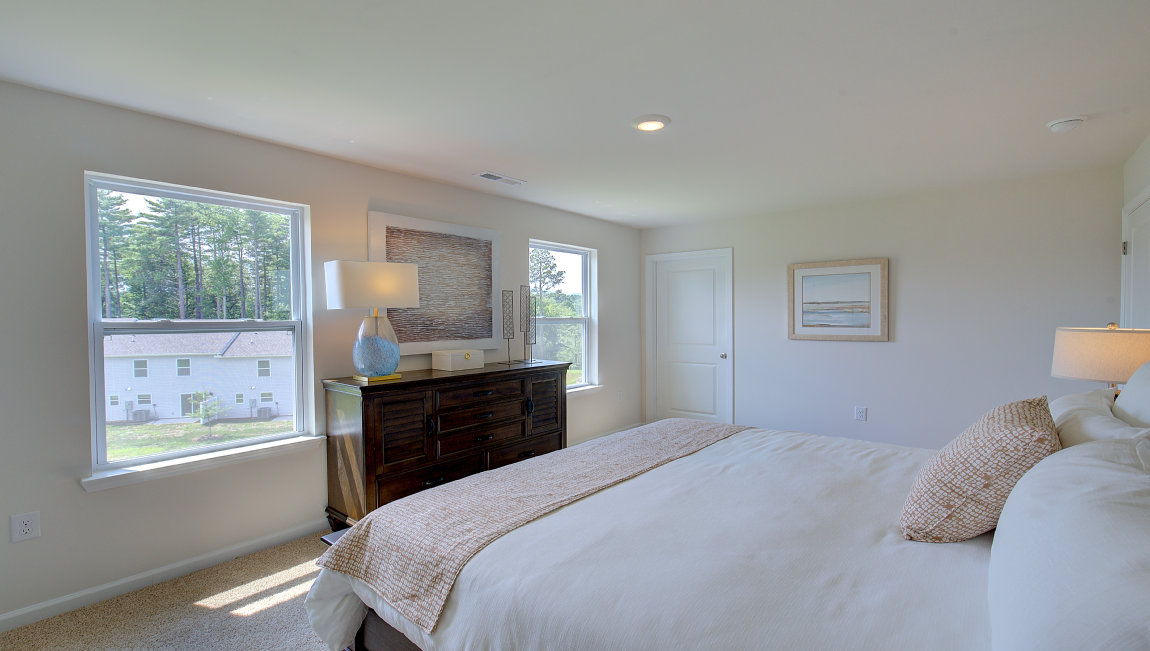 Primary bedroom with beige carpet and two windows. New Homes in Asheville, North Carolina