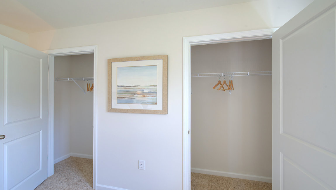 Primary walk in closets with beige carpet. New Homes in Asheville, North Carolina