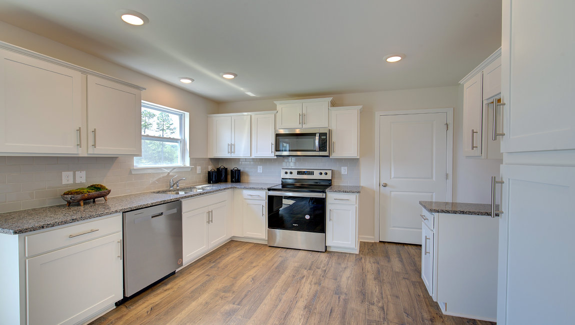 Kitchen with white cabinets, granite counters, subway tile backsplash and stainless steel appliances. New Homes in Asheville, North Carolina
