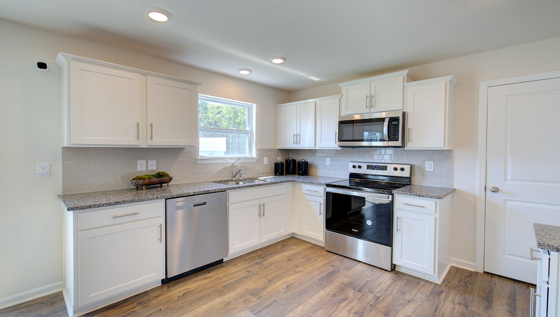 Kitchen with white cabinets, granite counters, subway tile backsplash and stainless steel appliances. New Homes in Asheville, North Carolina