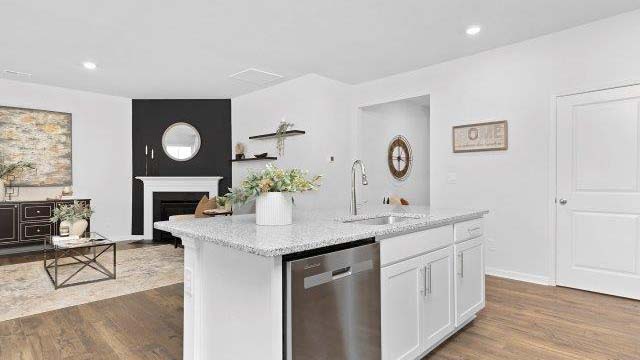 Kitchen and island with white cabinets, quarts countertops, wood floors, and stainless steel appliances