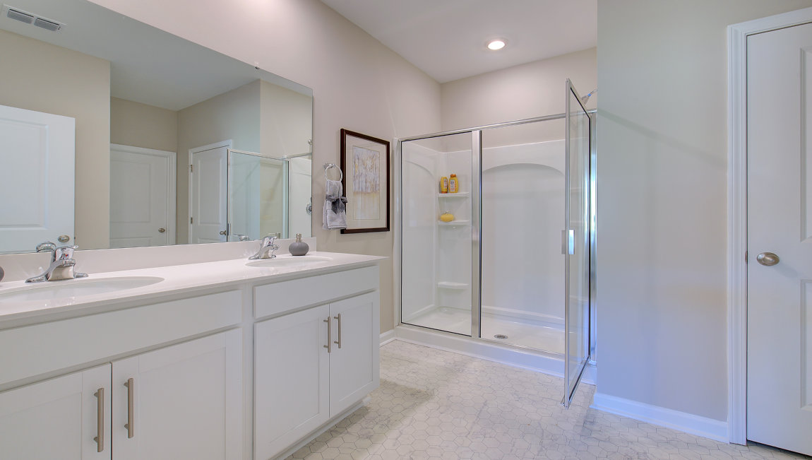 Bathroom with white cabinets and counters, and glass door shower