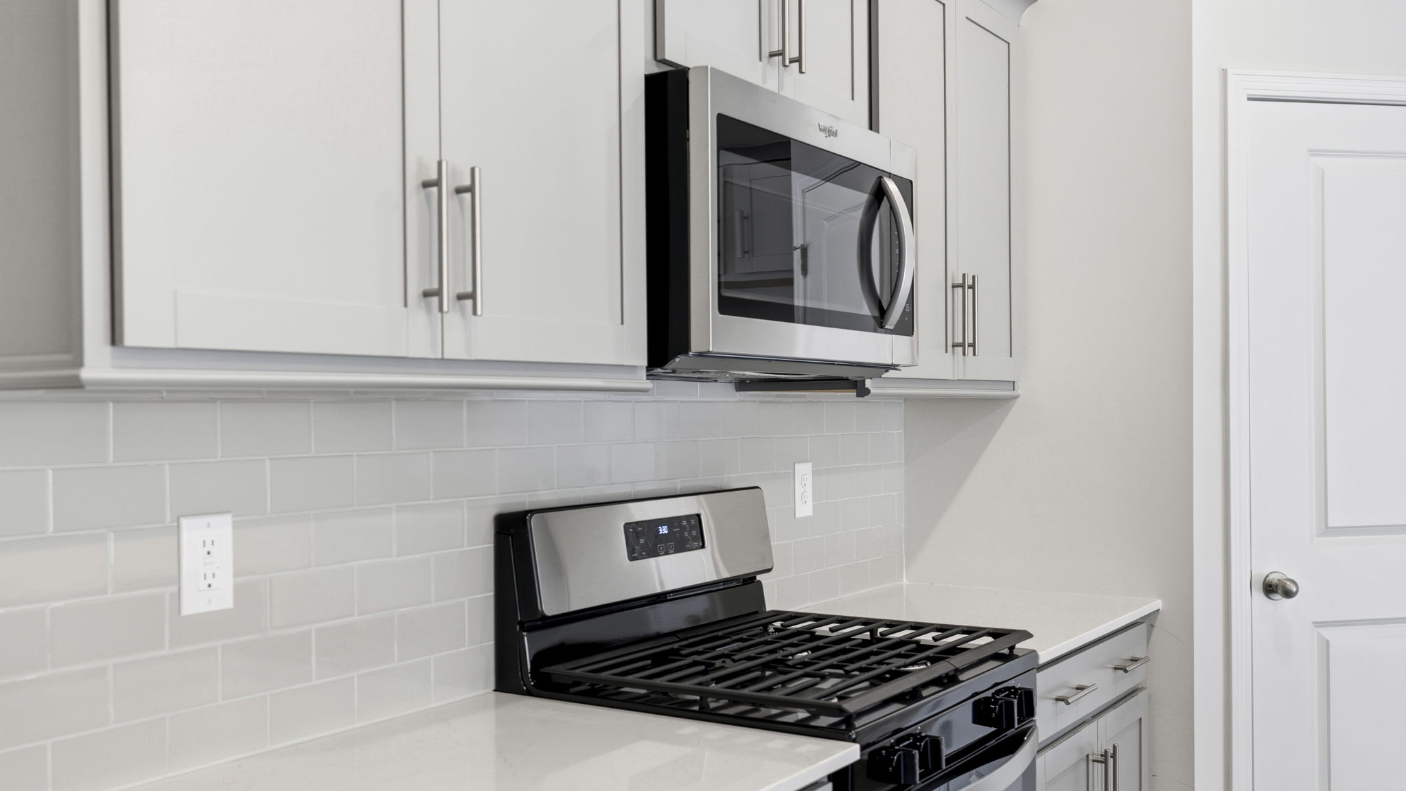 Close up view of kitchen with shaker cabinets and stainless steel appliances