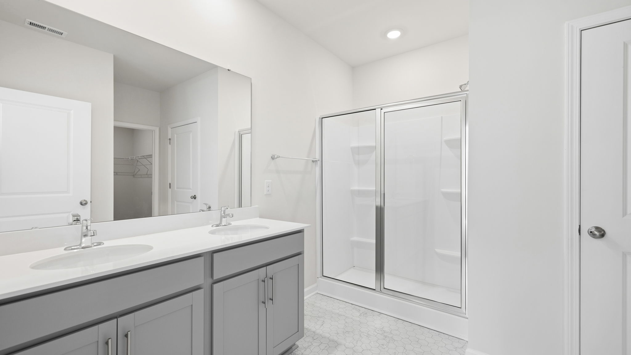 Bathroom with dual vanity, gray cabinets and walk in shower