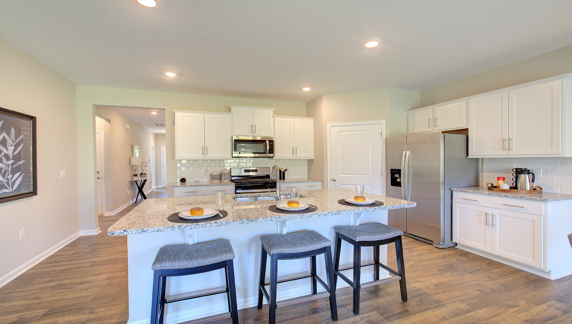 Kitchen and island with white cabinets and subway tiles and stainless steel appliances