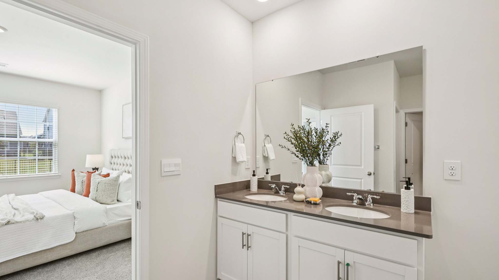 Bathroom with double vanity and view of the primary bedroom
