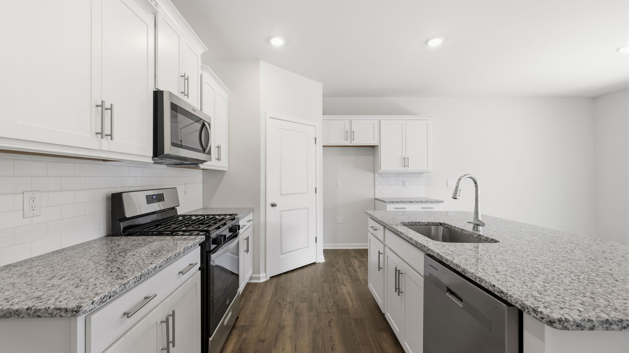 Open concept kitchen with large island, white cabinets and stainless steel appliances