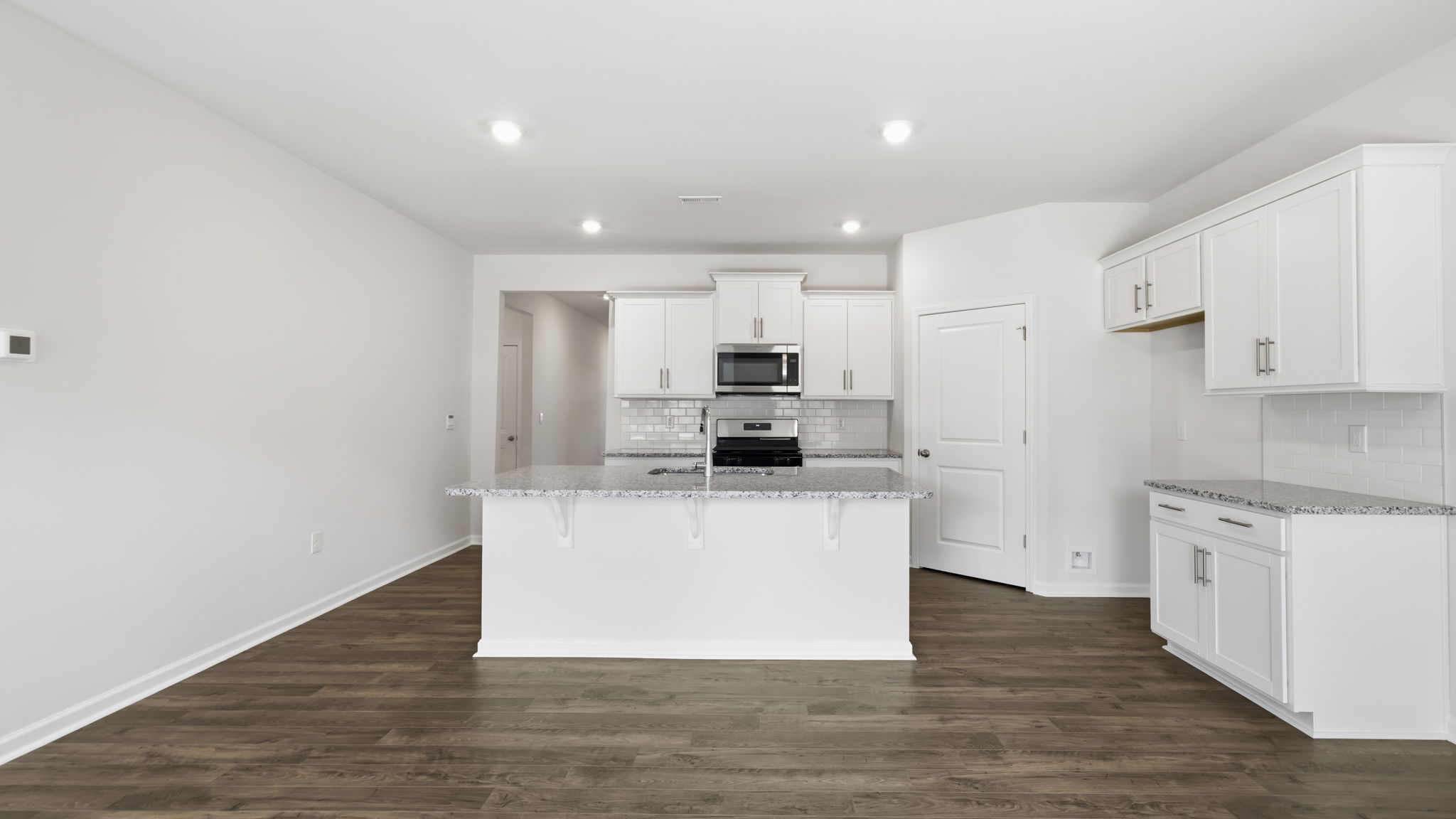 Open concept kitchen with large island, white cabinets and stainless steel appliances