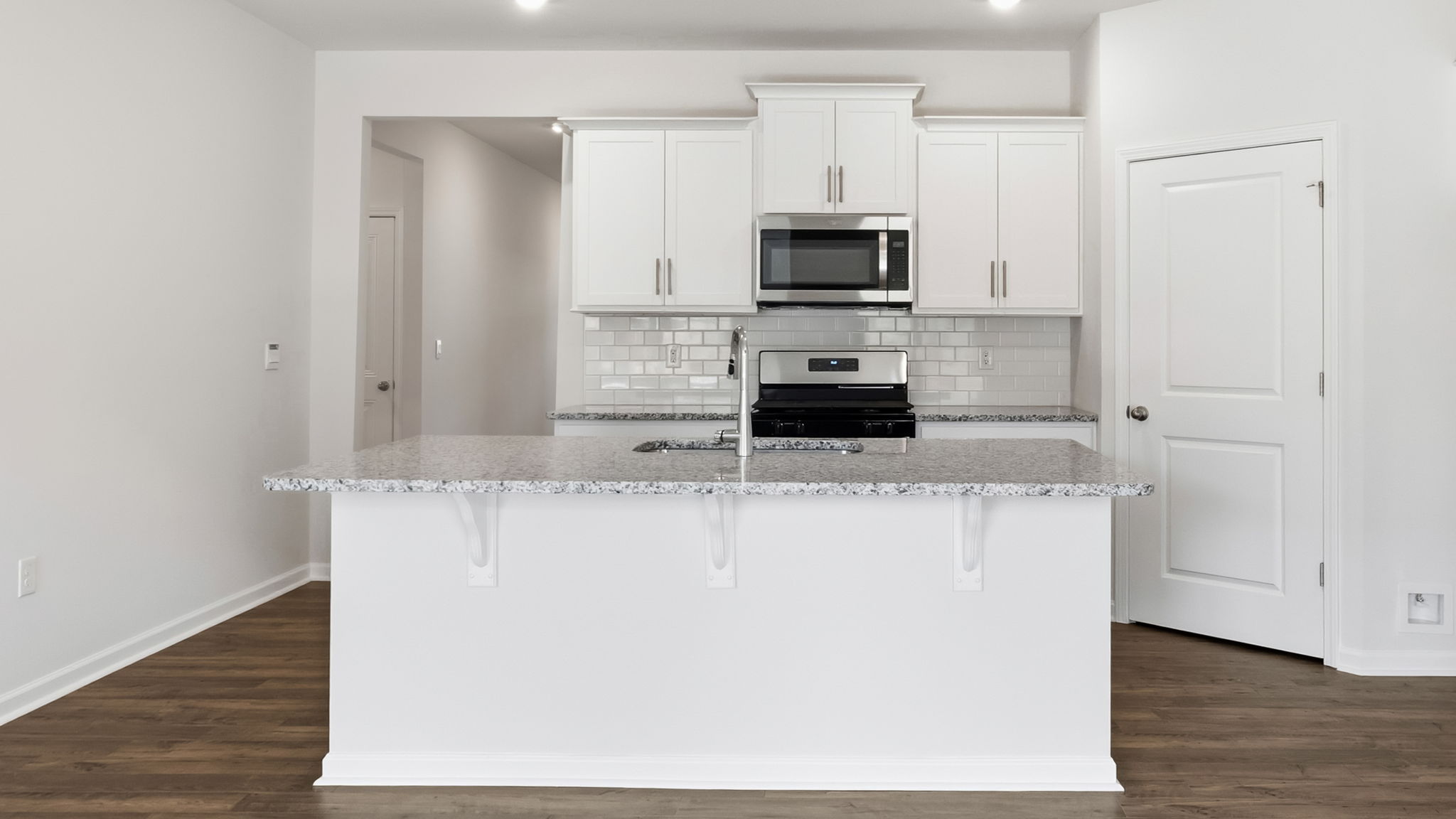 Open concept kitchen with large island, white cabinets and stainless steel appliances