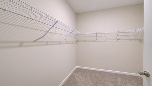 Primary bedroom walk in closet with built in racks for storage and hanging