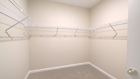 Primary bedroom walk in closet with built in racks for storage and hanging