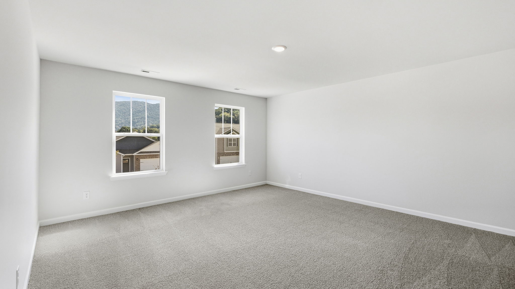 Carpeted primary bedroom with large windows