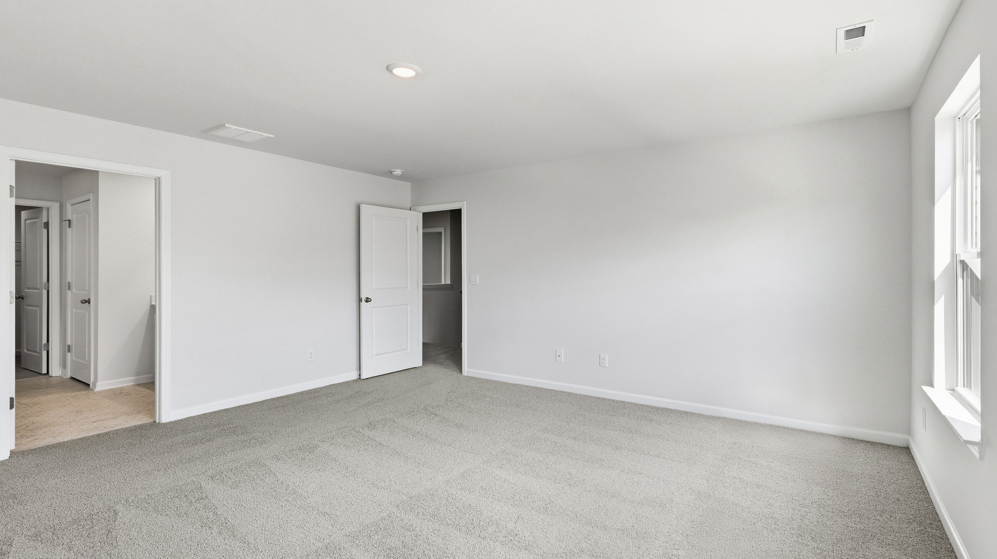 Carpeted primary bedroom with large windows