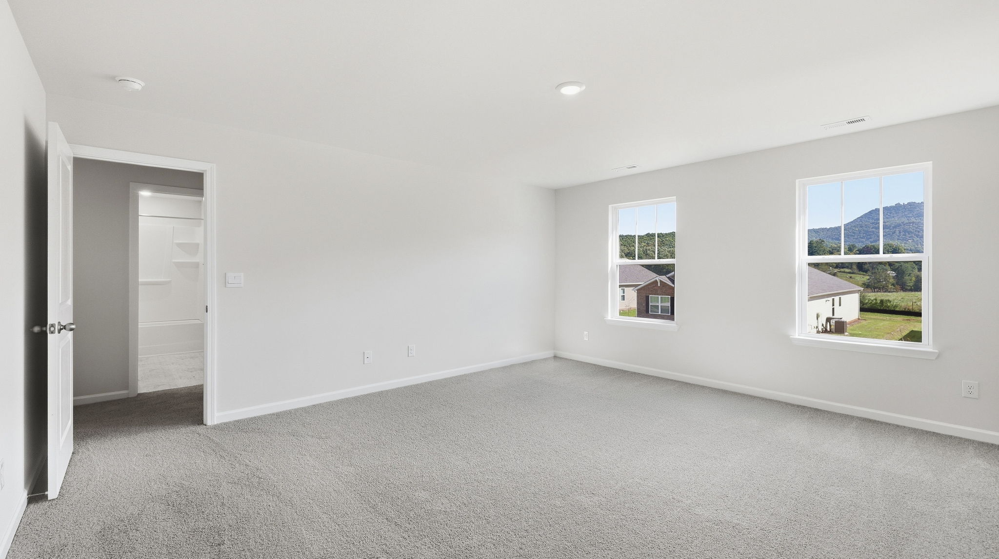 Carpeted primary bedroom with large windows