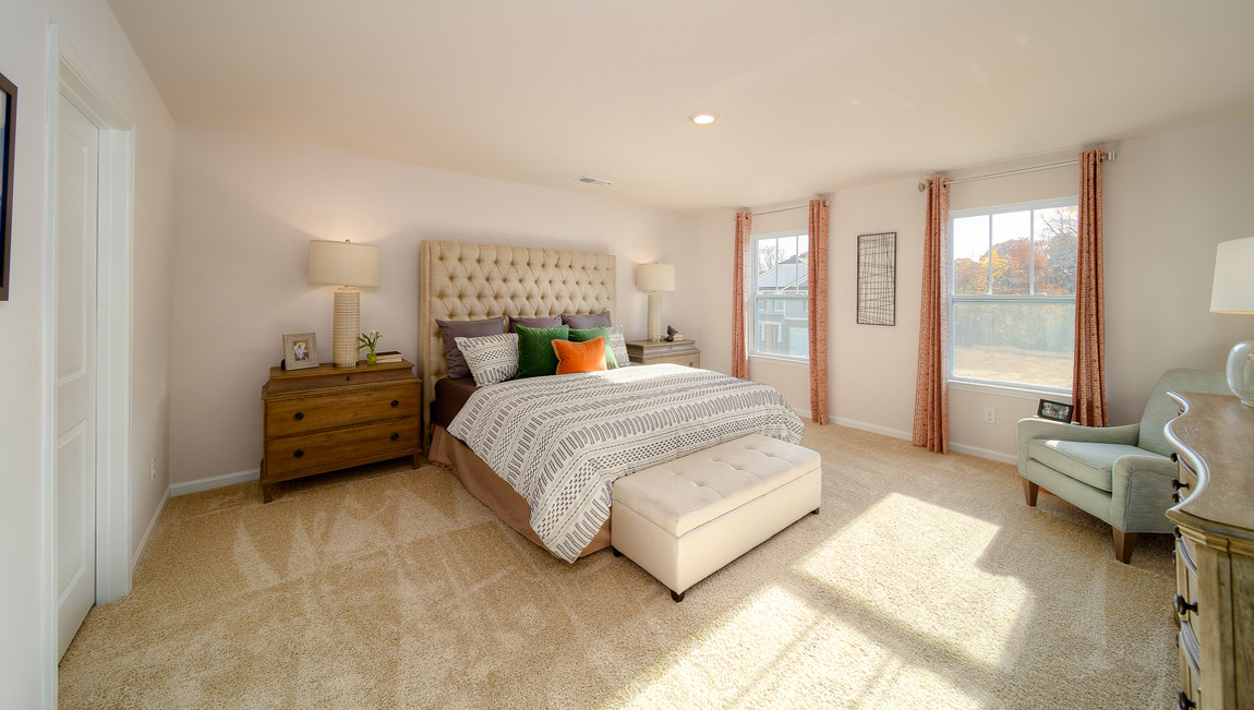 primary bedroom with carpet and two large windows
