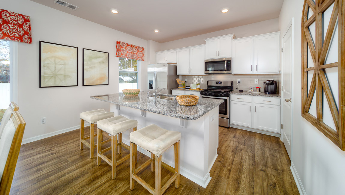 kitchen and island with white cabinets, wood floors and stainless steel appliances